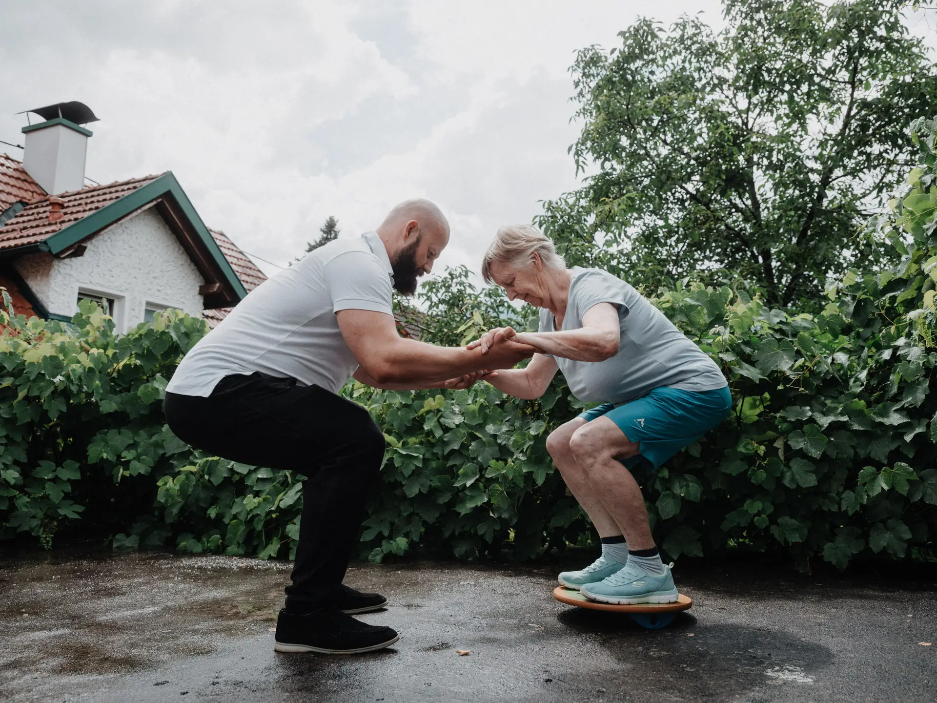 Thomas trainiert mit einer Kundin Kniebeugen im Garten